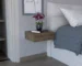 Dark brown floating nightstand with drawer mounted on wall next to bed