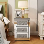 Modern crystal nightstand with drawers featuring mirrored finish and diamond details in a glamorous bedroom setting