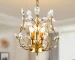Elegant gold crystal chandelier with three lights hanging in a modern living room
