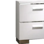 Glam white nightstand with chrome handles and high gloss lacquer finish, featuring two drawers, placed beside a bed in a modern bedroom.