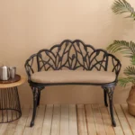 Black cast aluminum bench with floral rose design in a garden setting