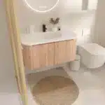 Goldoma wall-mounted bathroom vanity with round basin, white finish, installed in a modern bathroom setting, front view.
