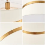 Modern chandelier with white fabric shade and brass finish hanging over kitchen island