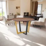 Round dining table for 4 with brown wood top and gold iron sled base in a cozy dining room