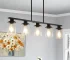 Modern industrial chandelier with 5 clear glass shades and matte black metal frame hanging over a dining table