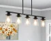 Modern industrial chandelier with 5 clear glass shades and matte black metal frame hanging over a dining table