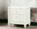 Ivory nightstand with drawers featuring ornate carving and curved legs in a bedroom setting