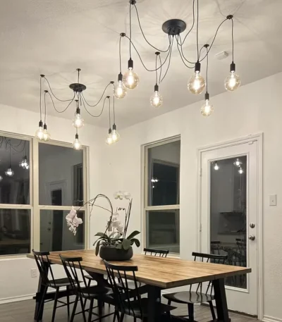 Industrial retro black spider chandelier with 8 adjustable arms and bulb sockets, hanging from ceiling in a living room