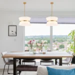 Modern chandelier with white fabric shade and brass finish hanging over kitchen island