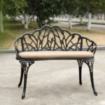 Black cast aluminum bench with floral rose design in a garden setting