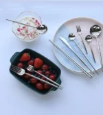 Elegant stainless steel flatware set with forks, spoons, and knives arranged on a wooden table