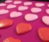 Heart-shaped non stick muffin pan filled with colorful macarons on a baking tray