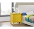 Modern yellow nightstand with three drawers in a bright bedroom