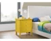Modern yellow nightstand with three drawers in a bright bedroom