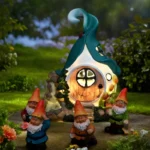 Close-up of gnome house statue with glowing solar light, textured stone finish visible.