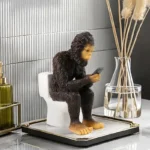 Close-up of the sasquatch statue's face, showing detailed resin fur and a mischievous expression, with a blurred garden
