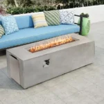 Rectangular MgO propane fire pit table with glowing flames on a patio