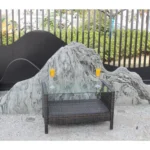 Outdoor coffee table with clear tempered glass top and brown PE rattan frame on a patio