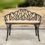 Black cast aluminum bench with floral rose design in a garden setting