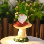 Solar garden gnome statue glowing at night, with mushroom base and hat light highlighting the resin material.