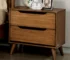 Mid century nightstand in solid oak with two drawers, placed beside a bed
