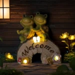 Goldoma turtle solar statue glowing warmly in a garden flower bed at dusk.