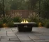 Modern metal propane fire pit on patio with glowing flames