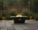 Modern metal propane fire pit on patio with glowing flames