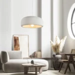 Pendant light suspended above a minimalist bedroom nightstand, casting soft ambient light on a beige bedspread.