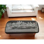 Goldoma 38-inch black wool ottoman with brown legs and nailhead trim used as a stylish footrest in a modern living room