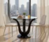 Round glass dining table with clear tempered top and black solid wood pedestal base in a modern dining room