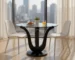 Round glass dining table with clear tempered top and black solid wood pedestal base in a modern dining room