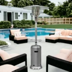 Patio heater lit with a blue flame, illuminating a wooden deck with chairs and a table in the background.