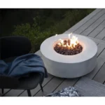 30-inch round propane fire pit table in grey color on a patio with cushions