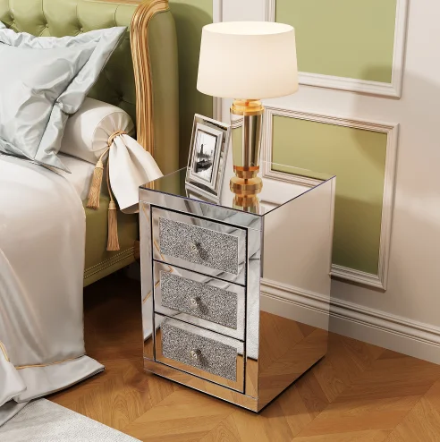 Modern crystal nightstand with drawers featuring mirrored finish and diamond details in a glamorous bedroom setting