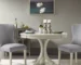 Modern round dining table in antique cream with wooden legs in a bright dining room