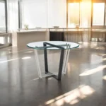 Round glass dining table with black iron sled base - 48 inch clear glass top, modern design, seats 4