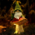 Goldoma solar gnome statue with warm LED glow on a mushroom base, placed on a garden path at dusk.