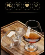 Elegant brandy snifter glass on a wooden table, filled with amber cognac