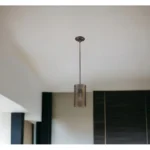 Close-up of the bronze metal hanging light, highlighting the textured mesh shade and warm glow.