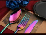 24-piece stainless steel cutlery set with gold handles displayed on a wooden table