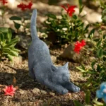 Hand-painted stretching cat statue in garden setting
