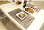 Gold weave placemats on a dining table with plates and cutlery