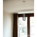 Close-up of the HMS gold metal cage pendant light with black accents, showing the bulb and cage texture against a dark
