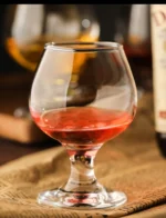 Elegant brandy snifter glass on a wooden table, filled with amber cognac