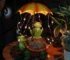 Solar frog garden statue glowing at night in a flower bed