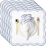 Set of scalloped embroidered napkins in natural color on a wooden table