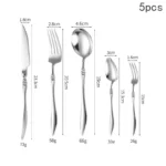 Elegant French stainless steel cutlery set with pointed tail handles on a wooden table
