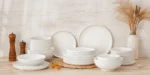 Elegant ceramic plates set with dinner plates, dessert plates, cereal bowls, and soup bowls arranged on a wooden table