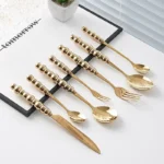 Stainless steel flatware set with ceramic pearl handles on wooden table